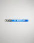 A vibrant blue wrestling keychain featuring the word WRESTLING in bold white letters and a black clip for attachment