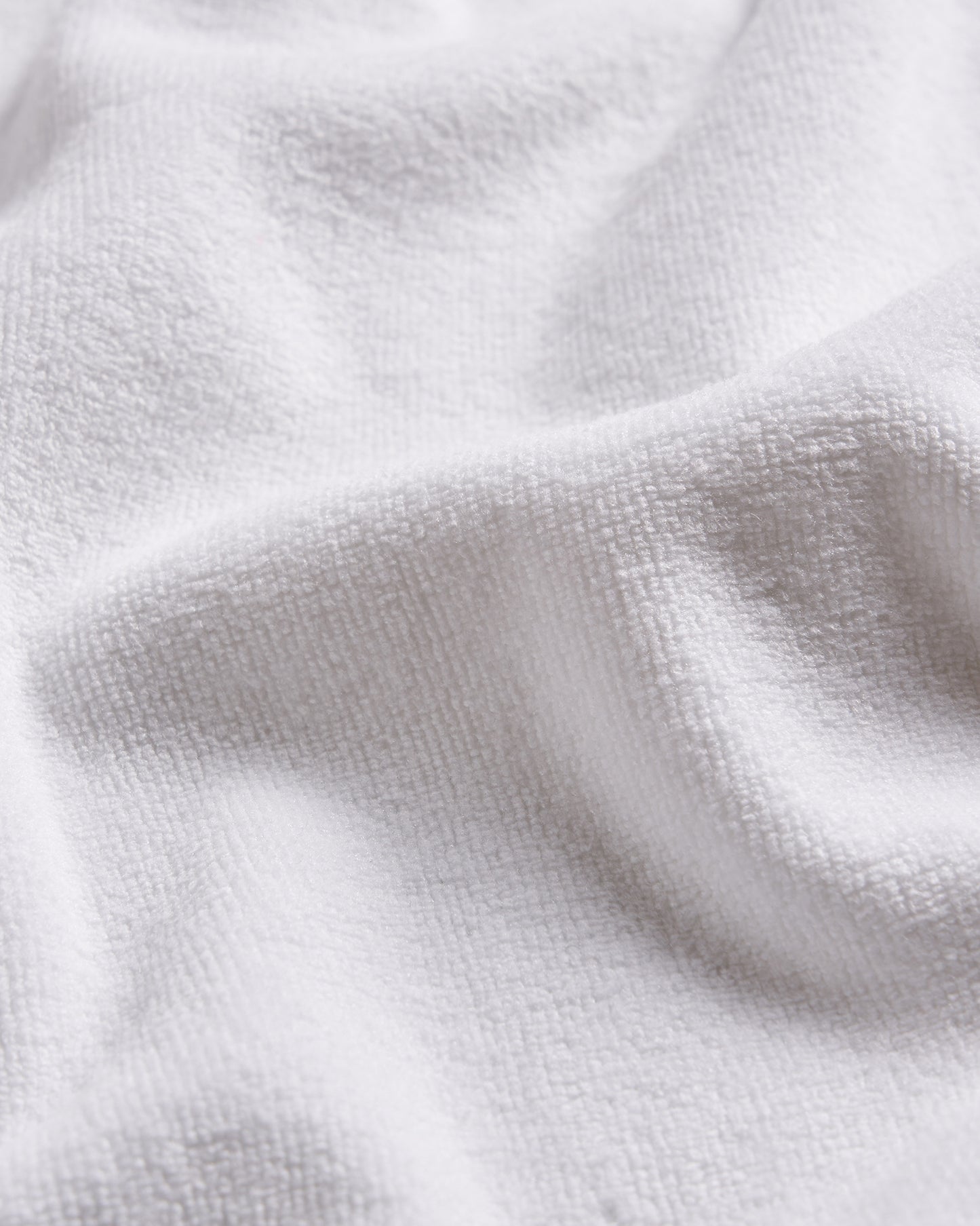 A close-up view of a soft textured white fabric showcasing its intricate weave and plush surface
