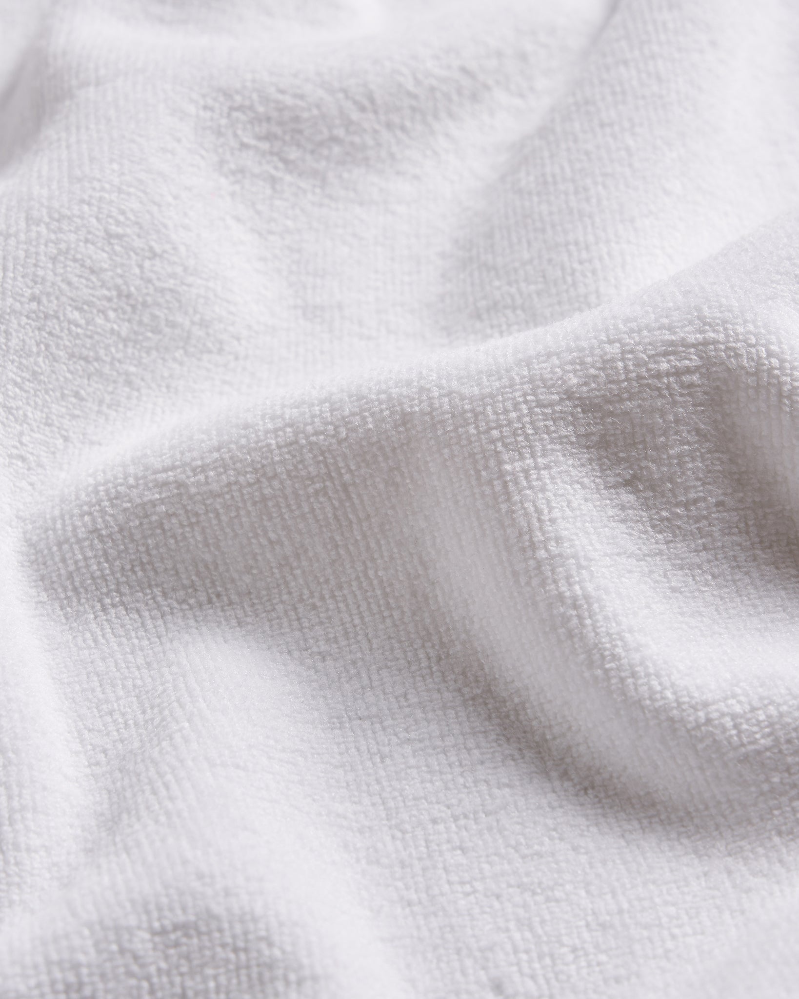 A close-up view of a soft textured white fabric showcasing its intricate weave and plush surface