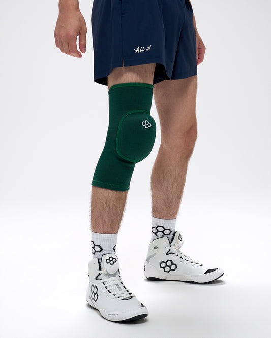 Person wearing a green knee pad on a white background