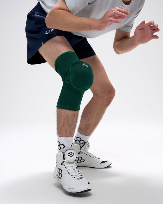 Person wearing a green knee pad on a white background