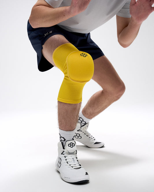 Person wearing yellow knee pads on a white background