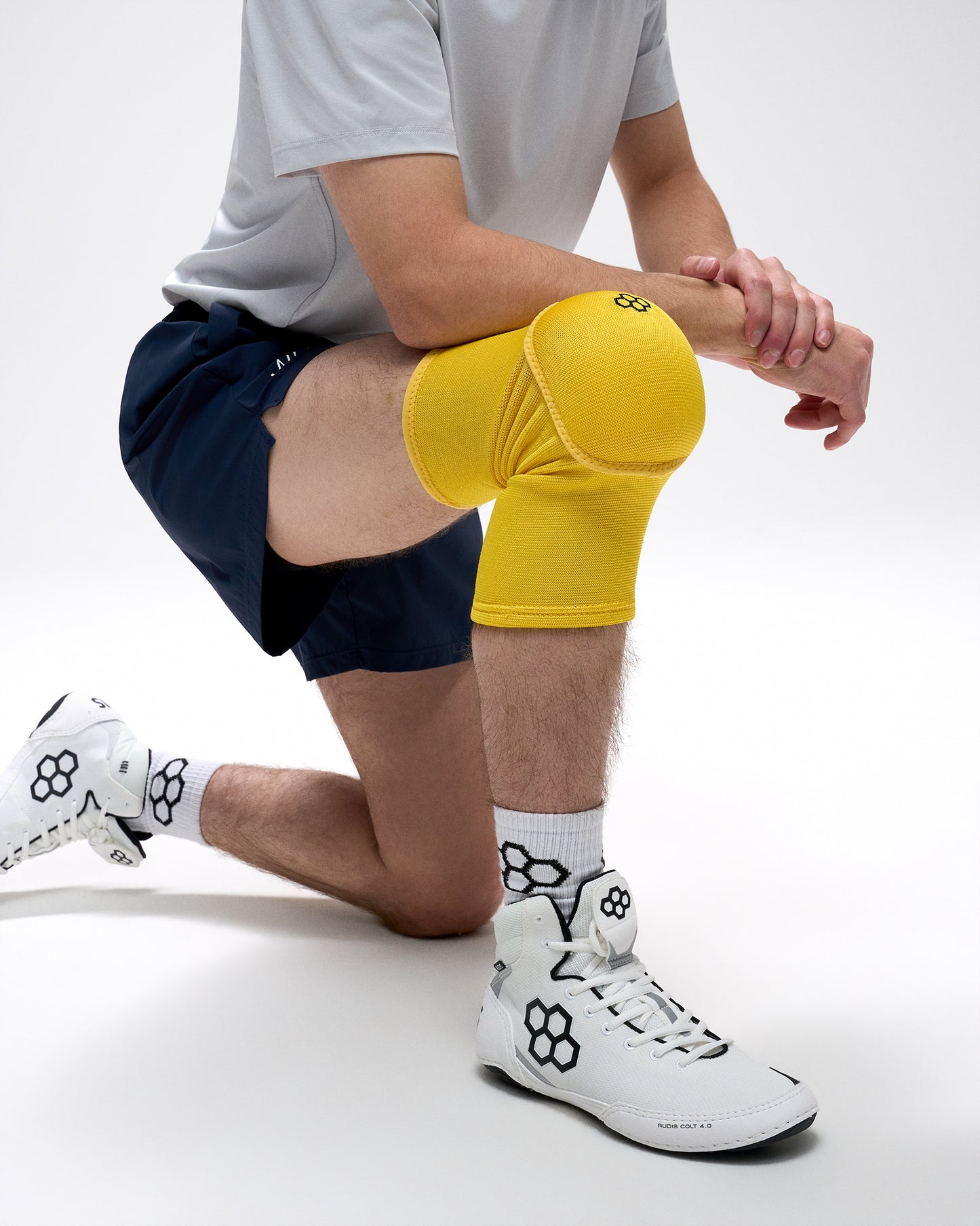 Person wearing yellow knee pads and white sneakers on a white background