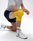 Person wearing yellow knee pads and white sneakers on a white background