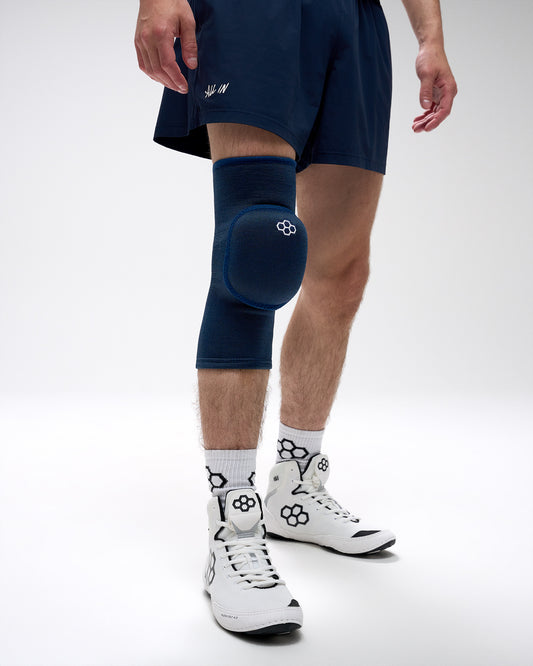 Person wearing a navy knee pad on a white background