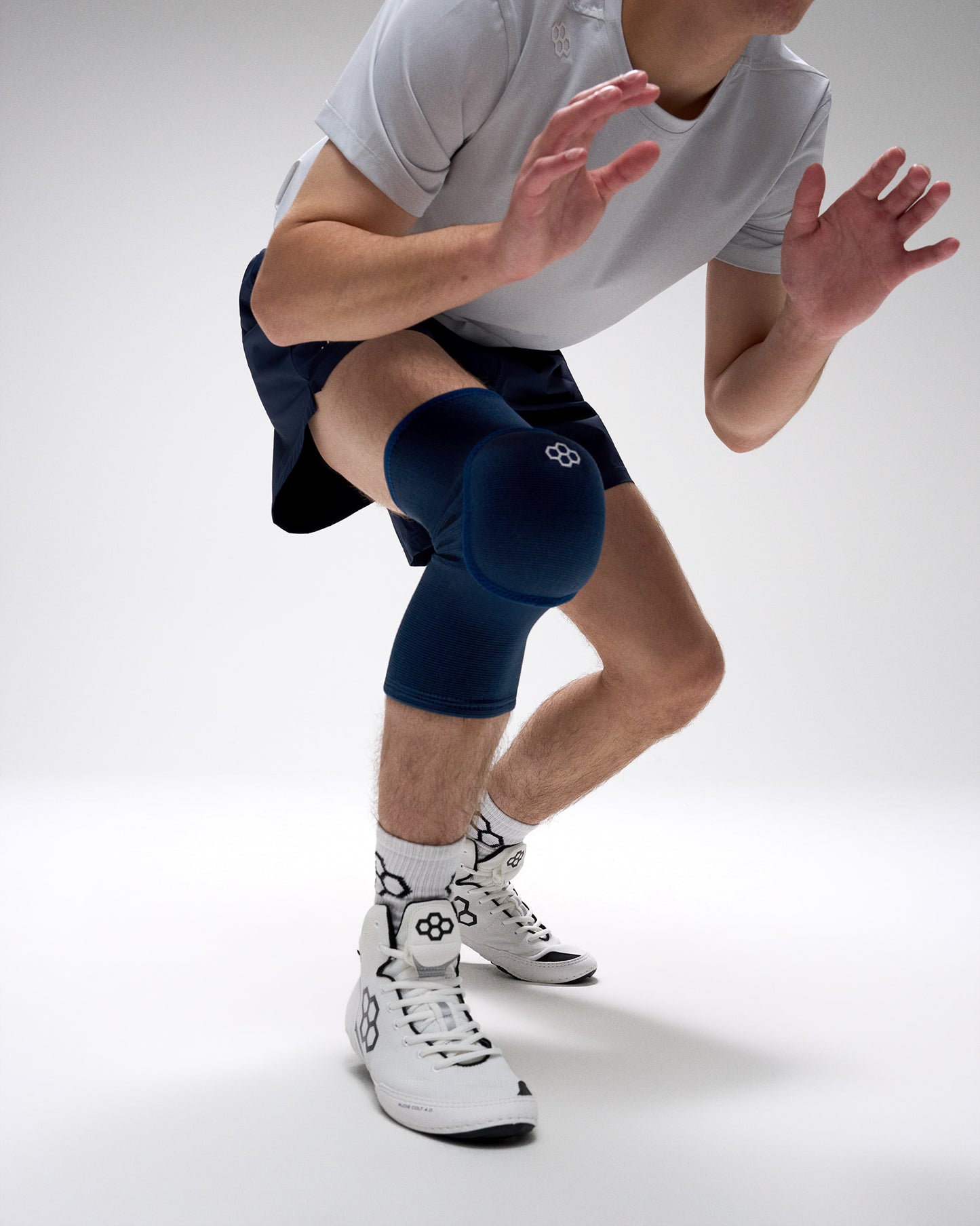 Person wearing blue knee pads and white sneakers on a plain background