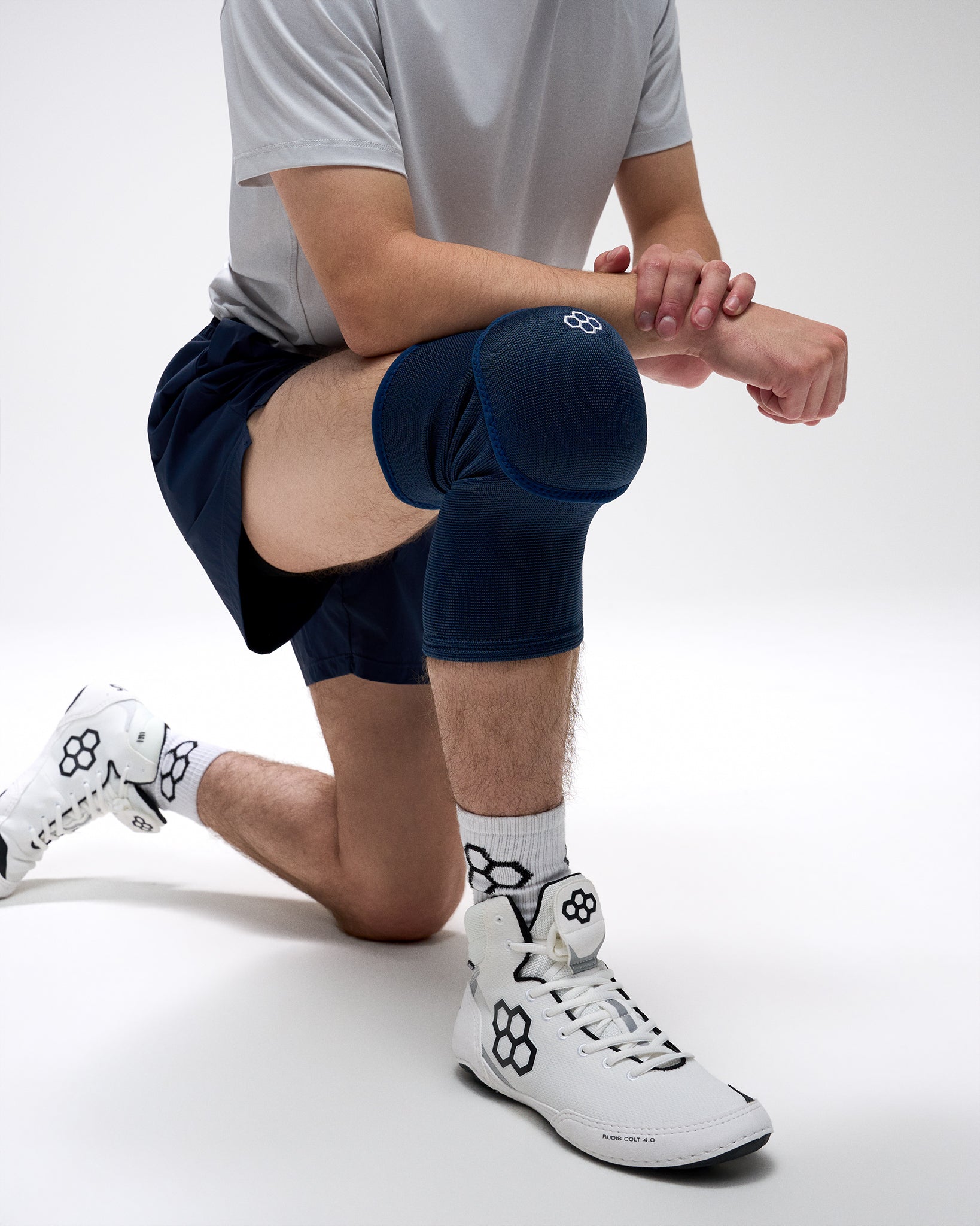 Person wearing navy knee sleeves on a white background