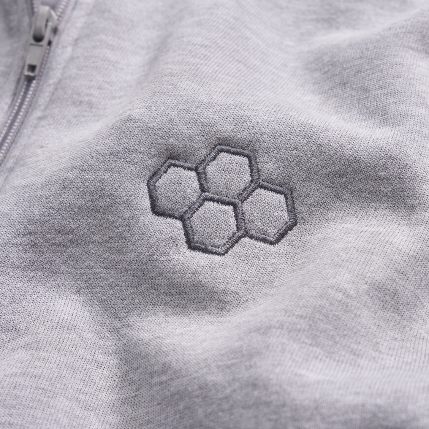 A close-up view of a light gray fabric featuring an embroidered hexagonal pattern