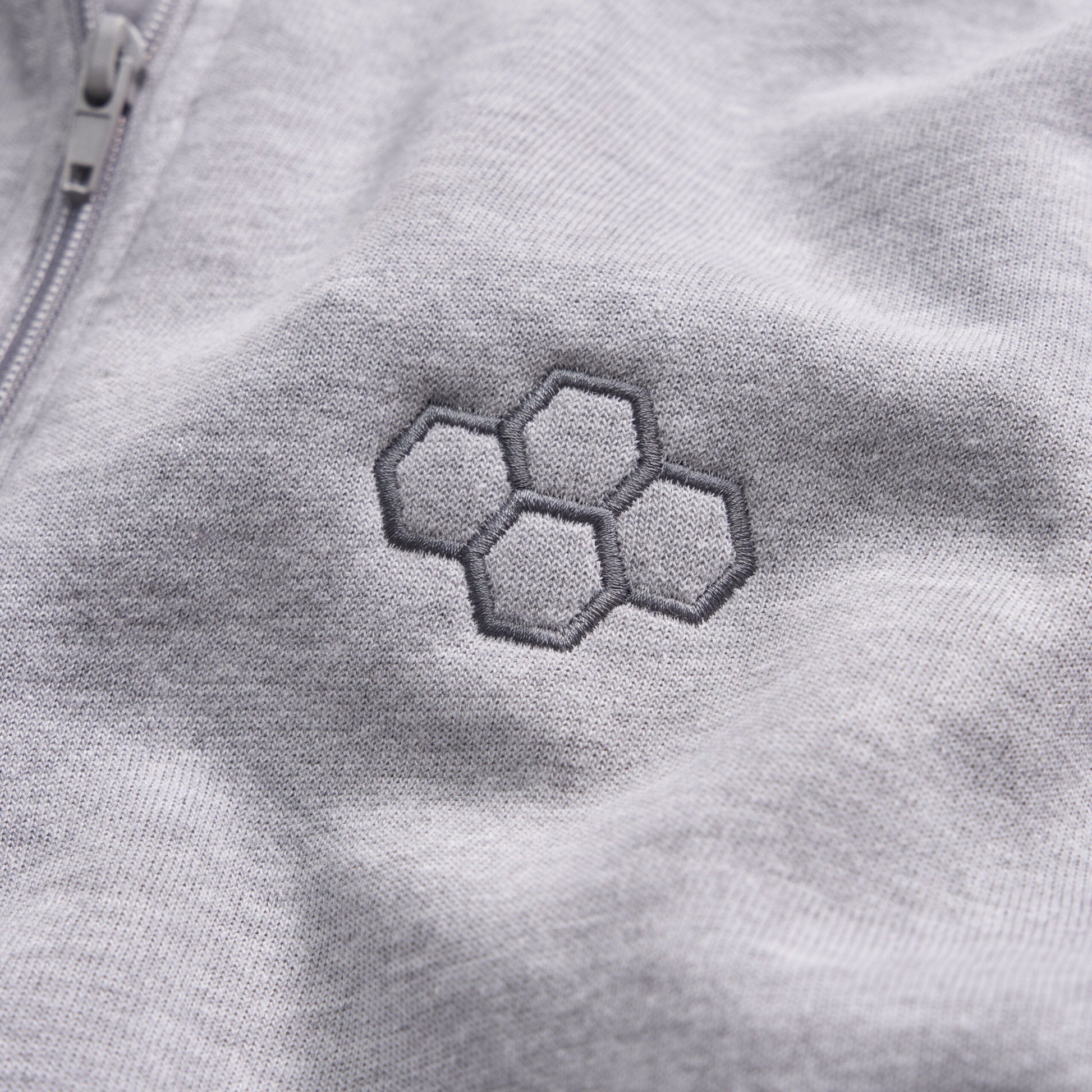 A close-up view of a light gray fabric featuring an embroidered hexagonal pattern