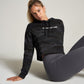 A model in a black camouflaged cropped hoodie with the text A WAY OF LIFE sits against a light gray background paired with fitted gray leggings