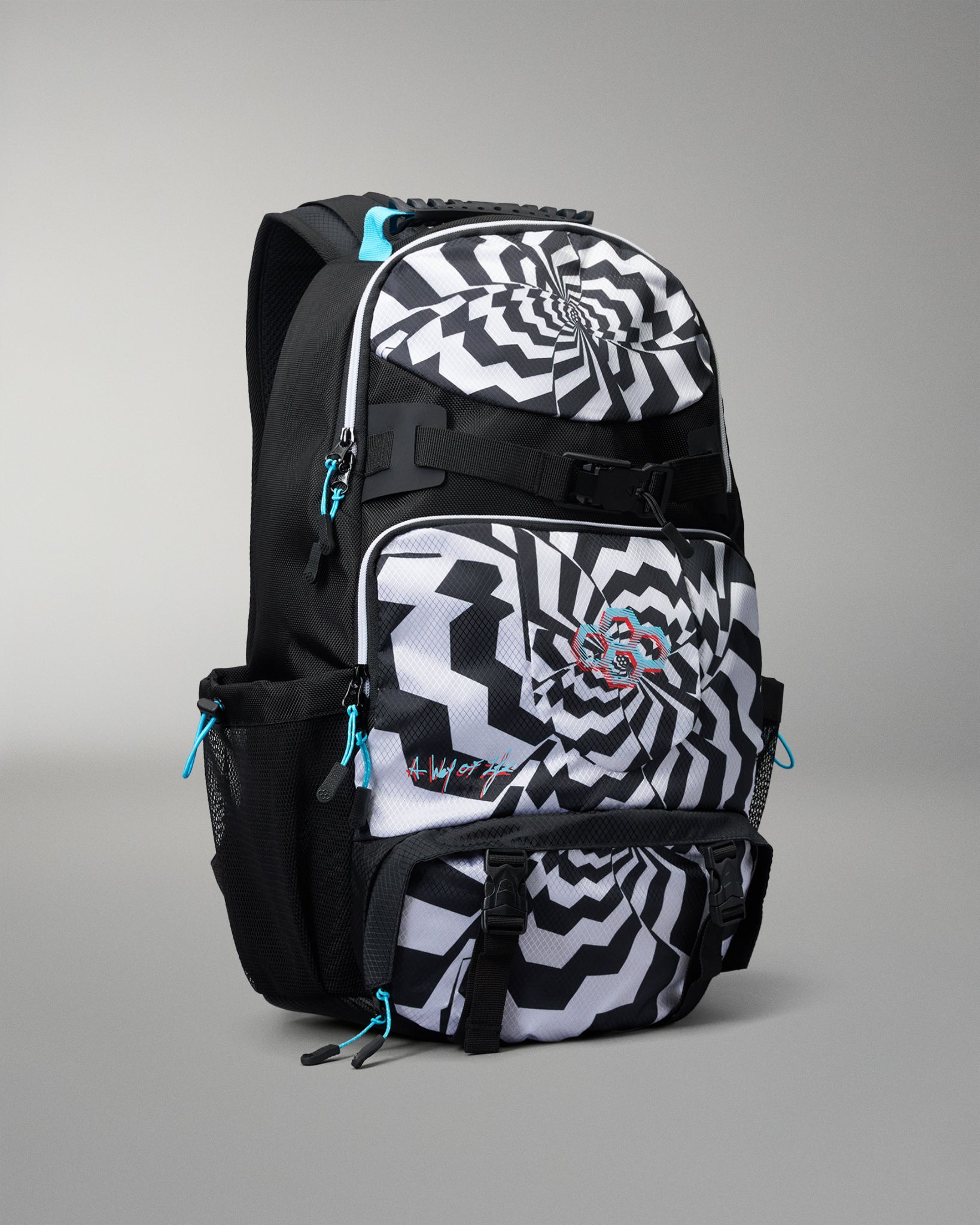 A black and white patterned backpack with a spiral design on the front pocket, black side pockets, and bright turquoise zipper pulls, shown on a neutral gray background.