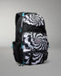 A black and white patterned backpack with a spiral design on the front pocket, black side pockets, and bright turquoise zipper pulls, shown on a neutral gray background.