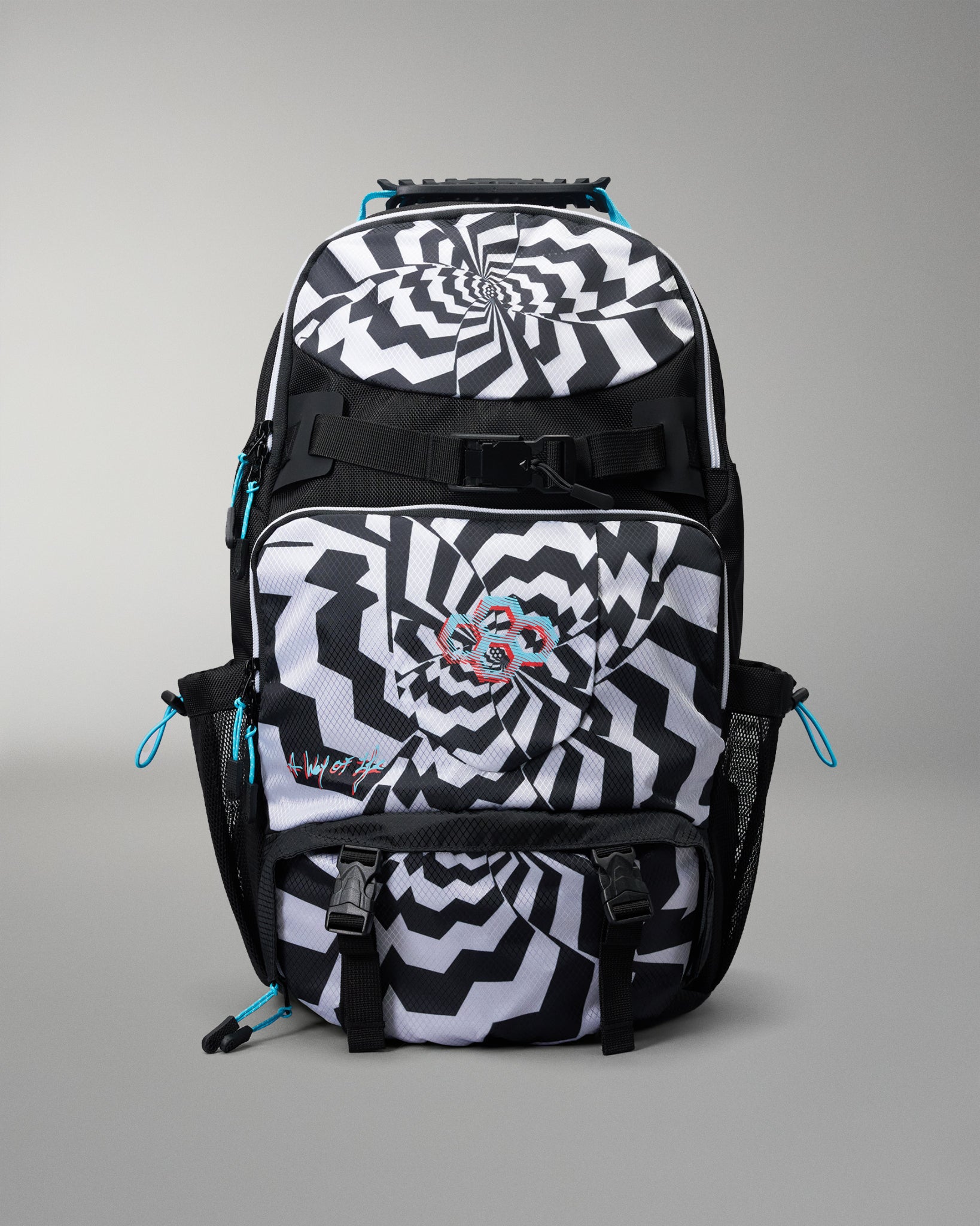 A black and white patterned backpack with a spiral optical illusion design, featuring a central butterfly graphic and bright blue zipper pulls, shown on a neutral gray background.