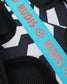 Close-up of a black and white geometric patterned textile with a bright turquoise strap printed repeatedly with the brand name RUDIS in coral.