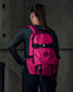 Person wearing a pink backpack with a logo on a dark background