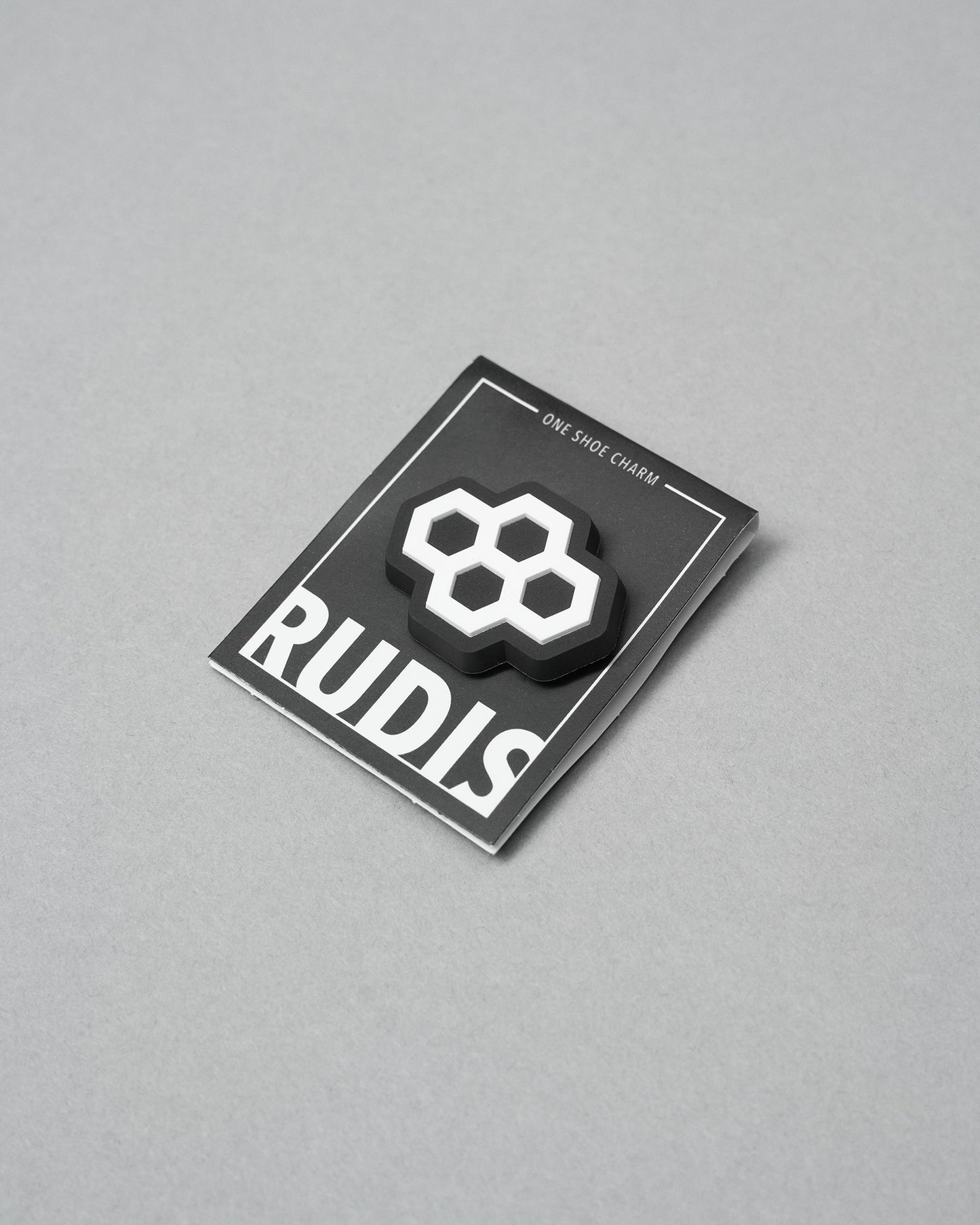 Black card with a white hexagonal symbol and 'RUDIS' branding on a gray background