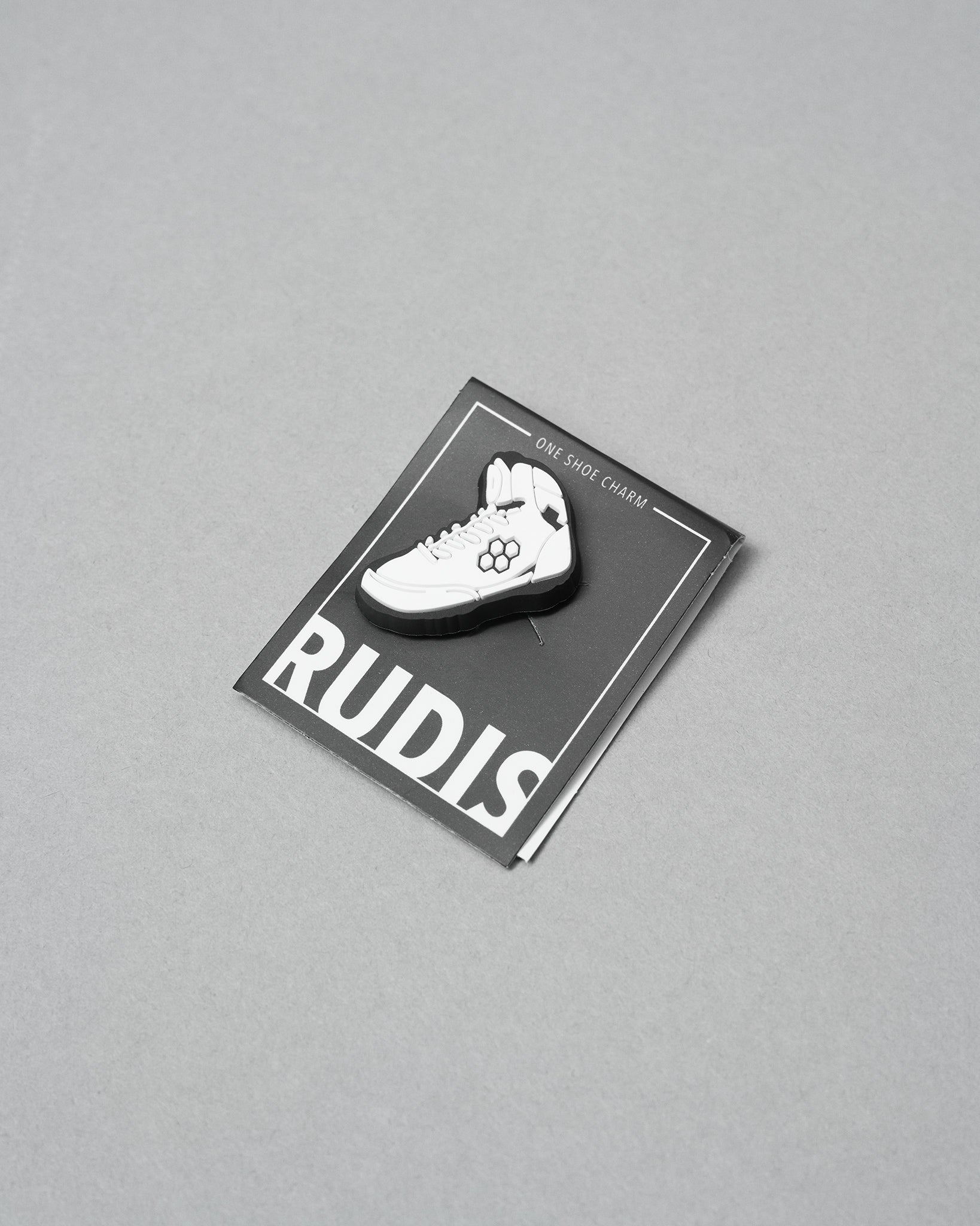 White shoe charm on a RUDIS branded card against a gray background