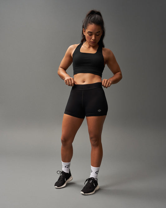 Woman wearing black athletic wear on a gray background