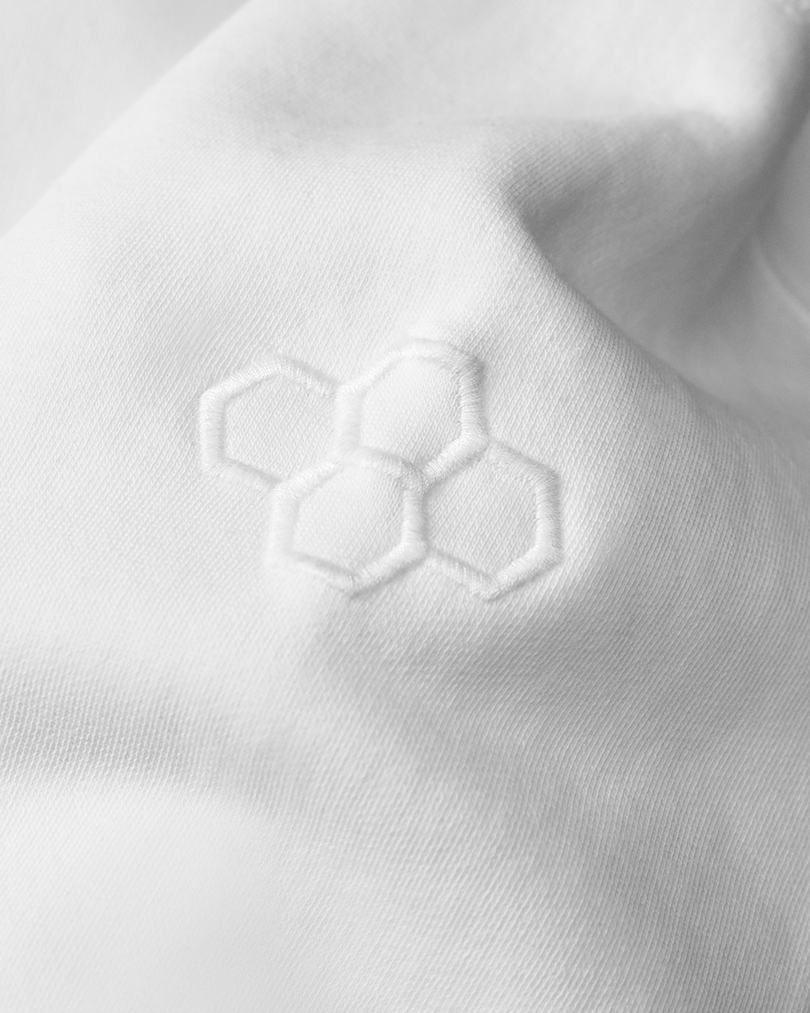 Close-up of a white fabric with an embroidered hexagonal pattern.