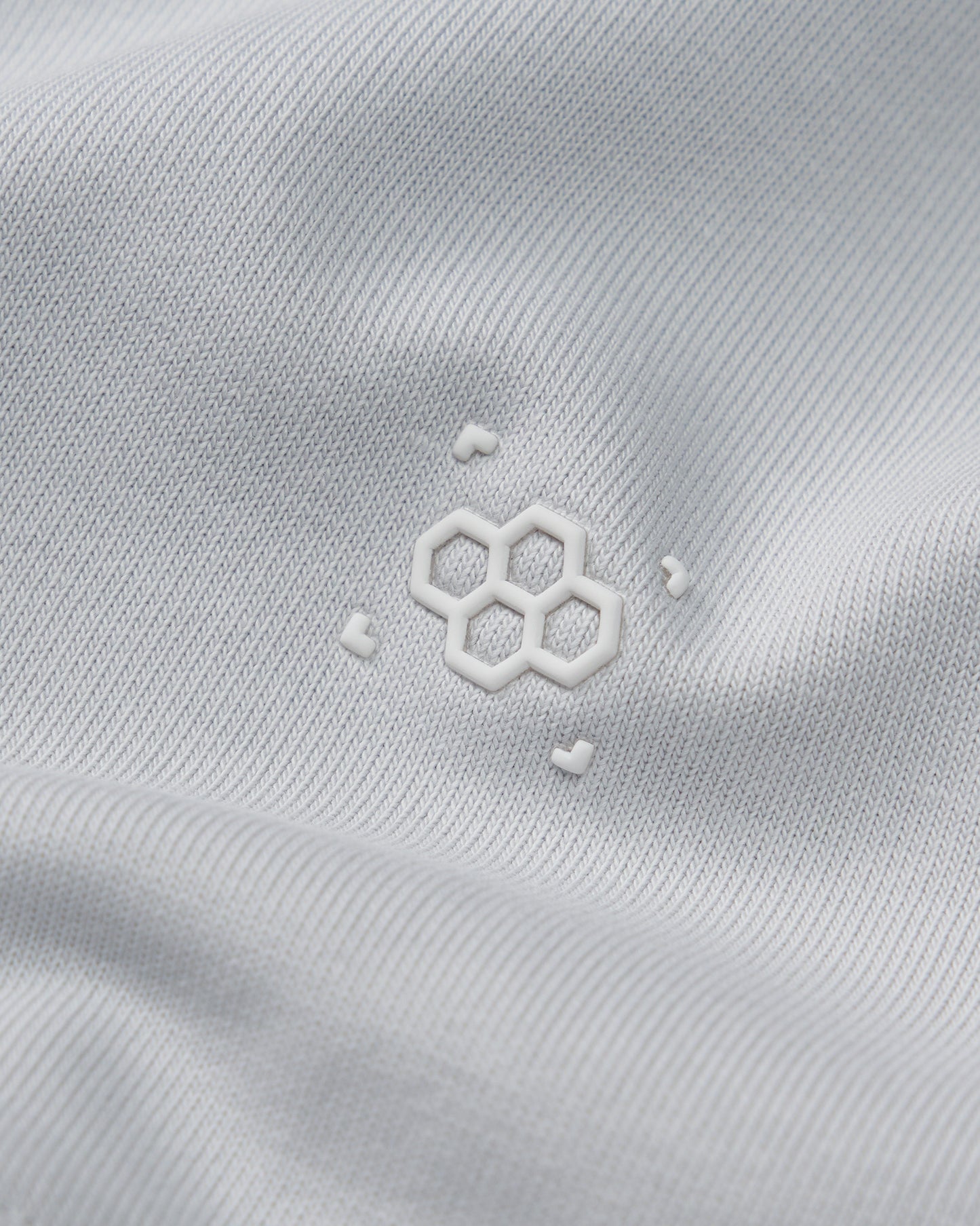 Close-up of a white fabric with a subtle logo on a light gray background