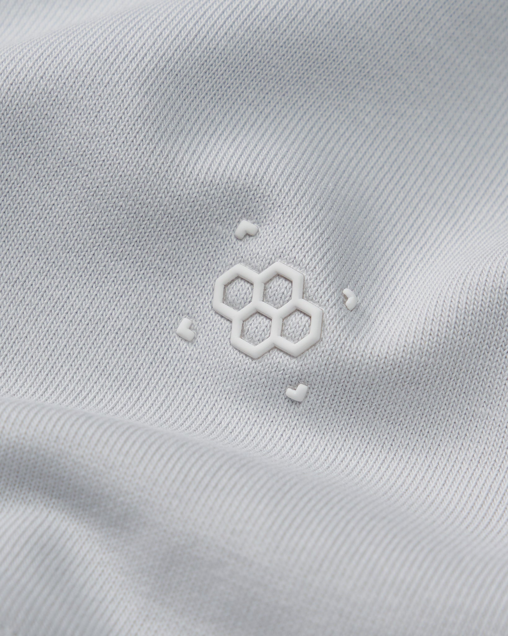 Close-up of a white fabric with a subtle logo on a light gray background