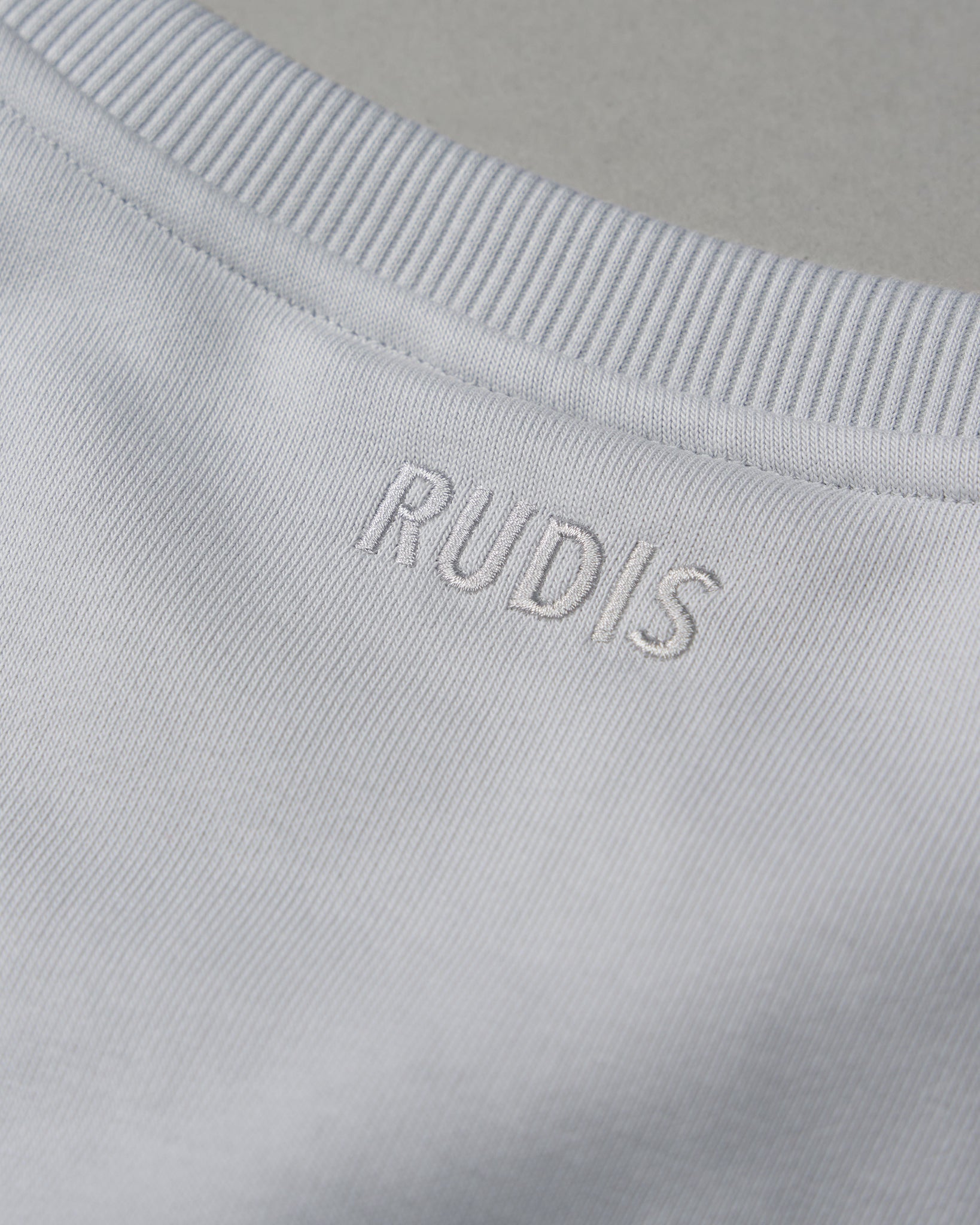 Close-up of a light gray fabric with 'RUDIS' branding.