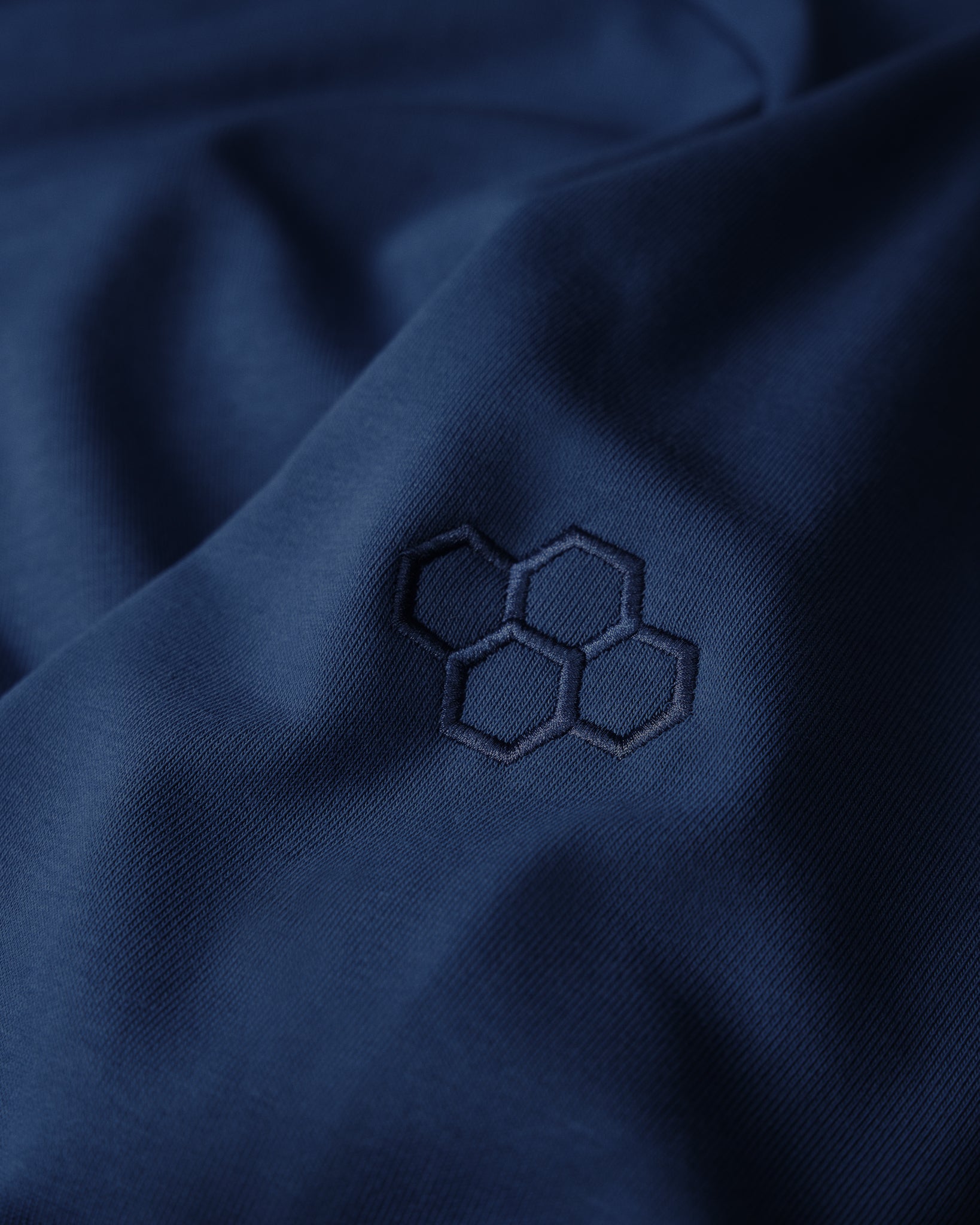 Close-up of a dark blue fabric with an embroidered hexagonal pattern.