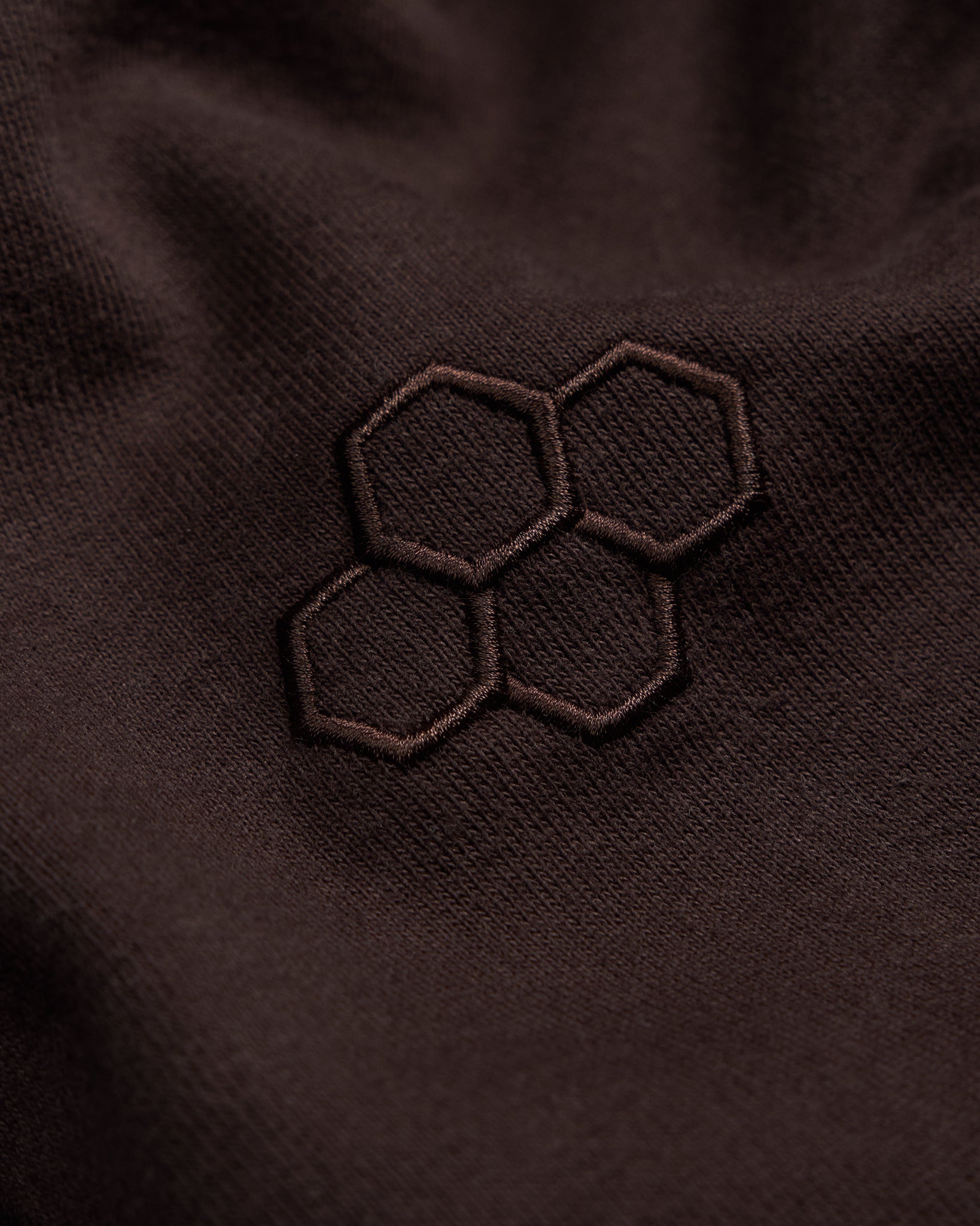 Close-up of a brown fabric with an embroidered hexagonal pattern.