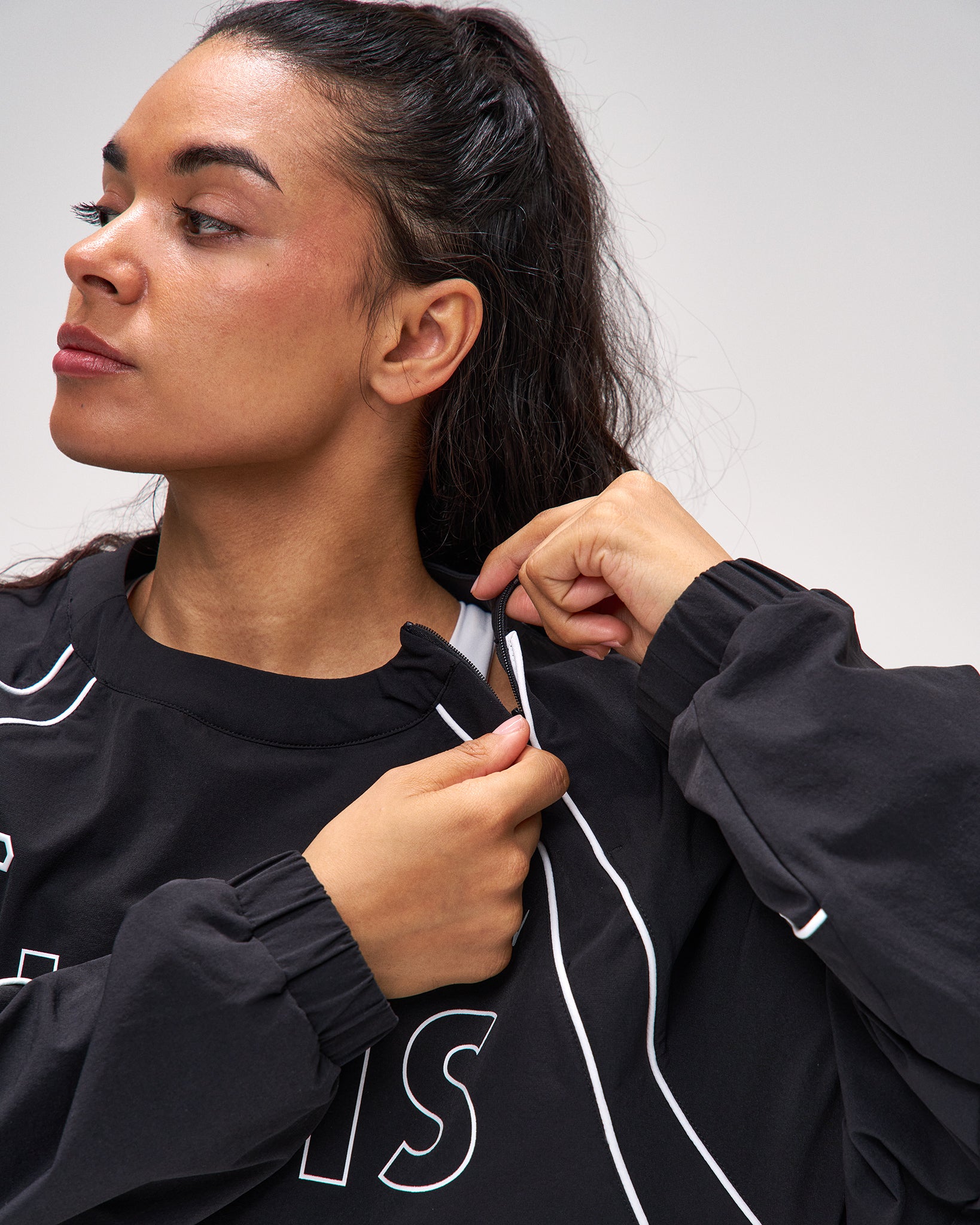 Woman wearing a black hoodie with white drawstrings against a plain background