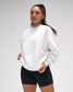 Woman wearing a white sweatshirt and black shorts on a plain background