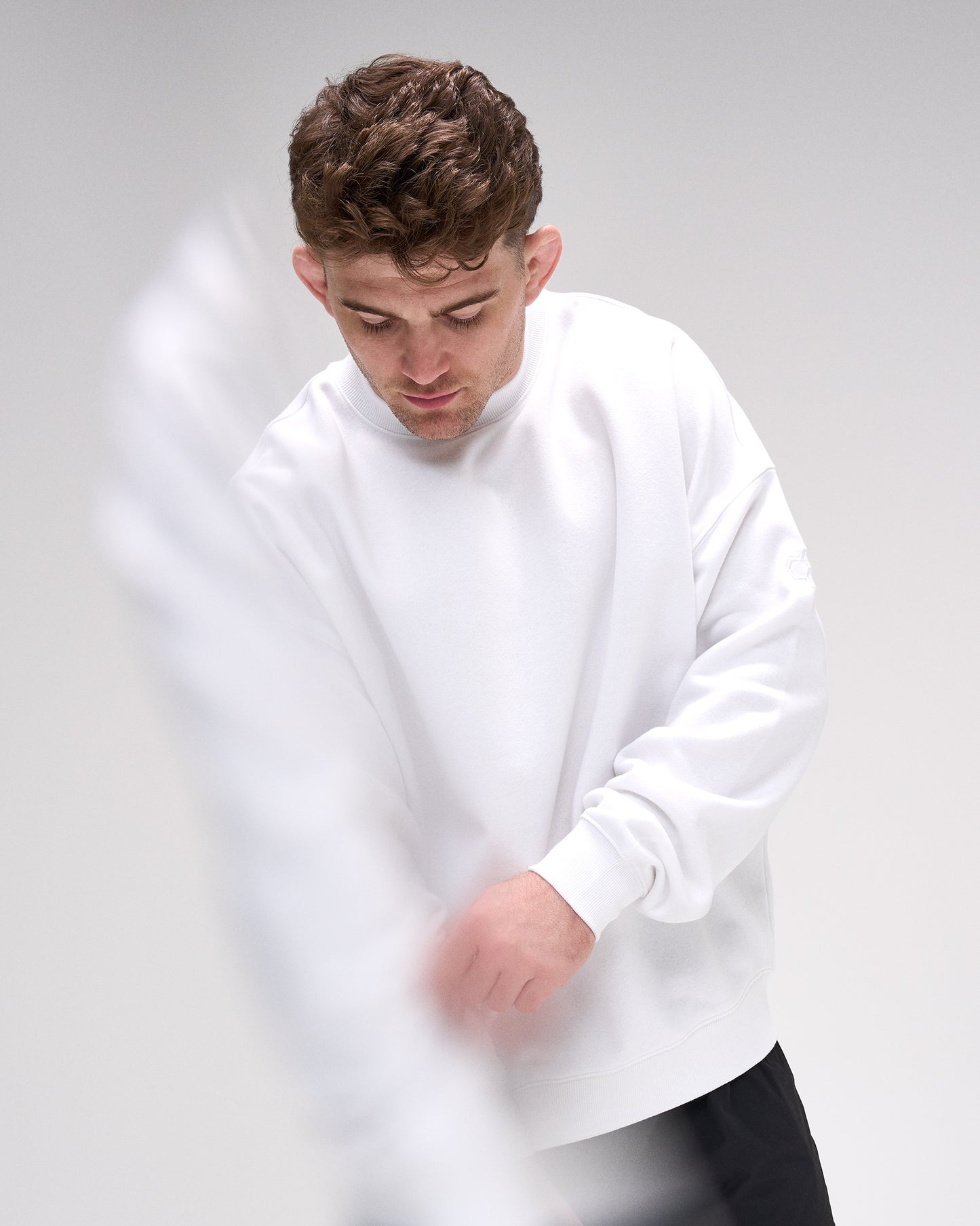 Man wearing a white sweatshirt against a plain background
