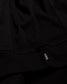 Close-up of a black garment with a brand logo on a dark background