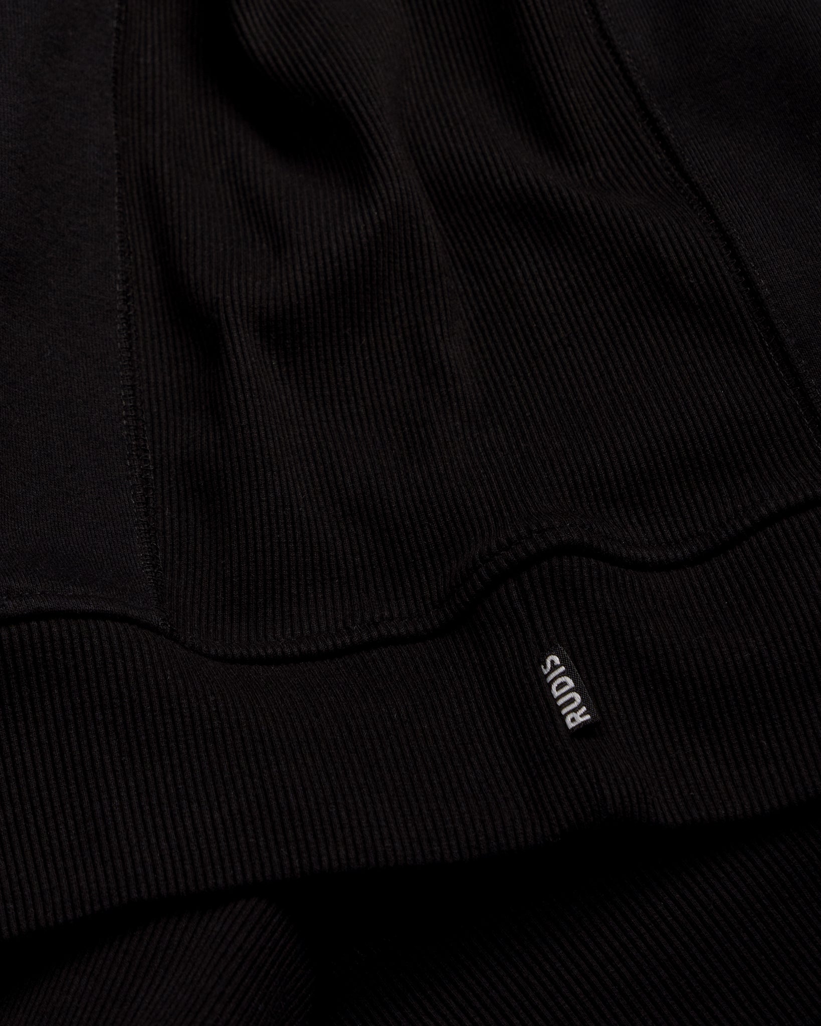 Close-up of a black garment with a brand logo on a dark background