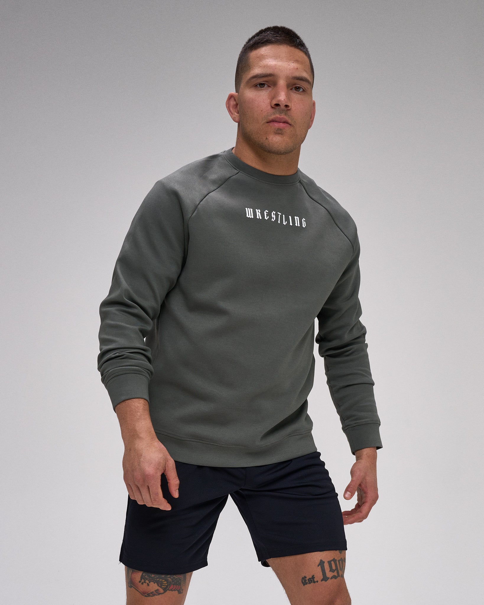 Man wearing a gray sweatshirt with 'Wrestling' text on a gray background