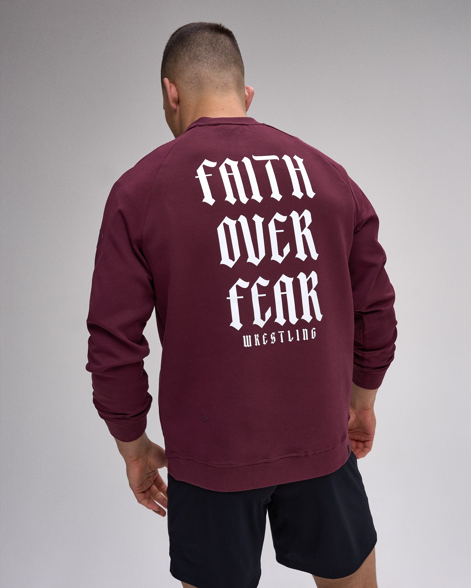 Maroon sweatshirt with 'Faith Over Fear Wrestling' text on the back, worn by a person.