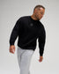 Man wearing the RUDIS Hex Relaxed Comfort Fleece Crewneck in Black with a tonal chest logo, relaxed silhouette, and ribbed cuffs.
 Copy alt text