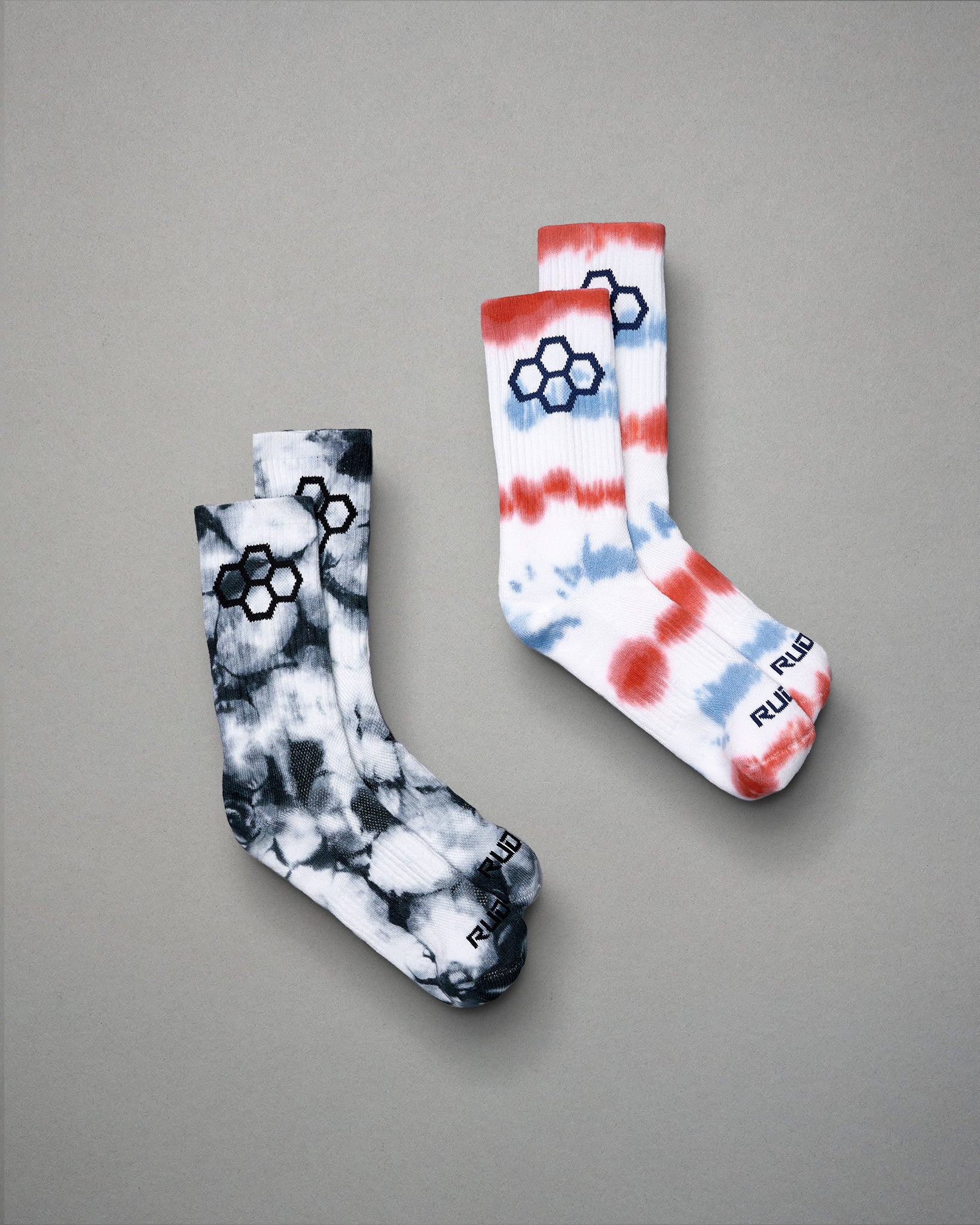 A pair of stylish socks featuring a tie-dye design in black and white alongside another pair in red white and blue with a modern logo