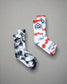 A pair of stylish socks featuring a tie-dye design in black and white alongside another pair in red white and blue with a modern logo