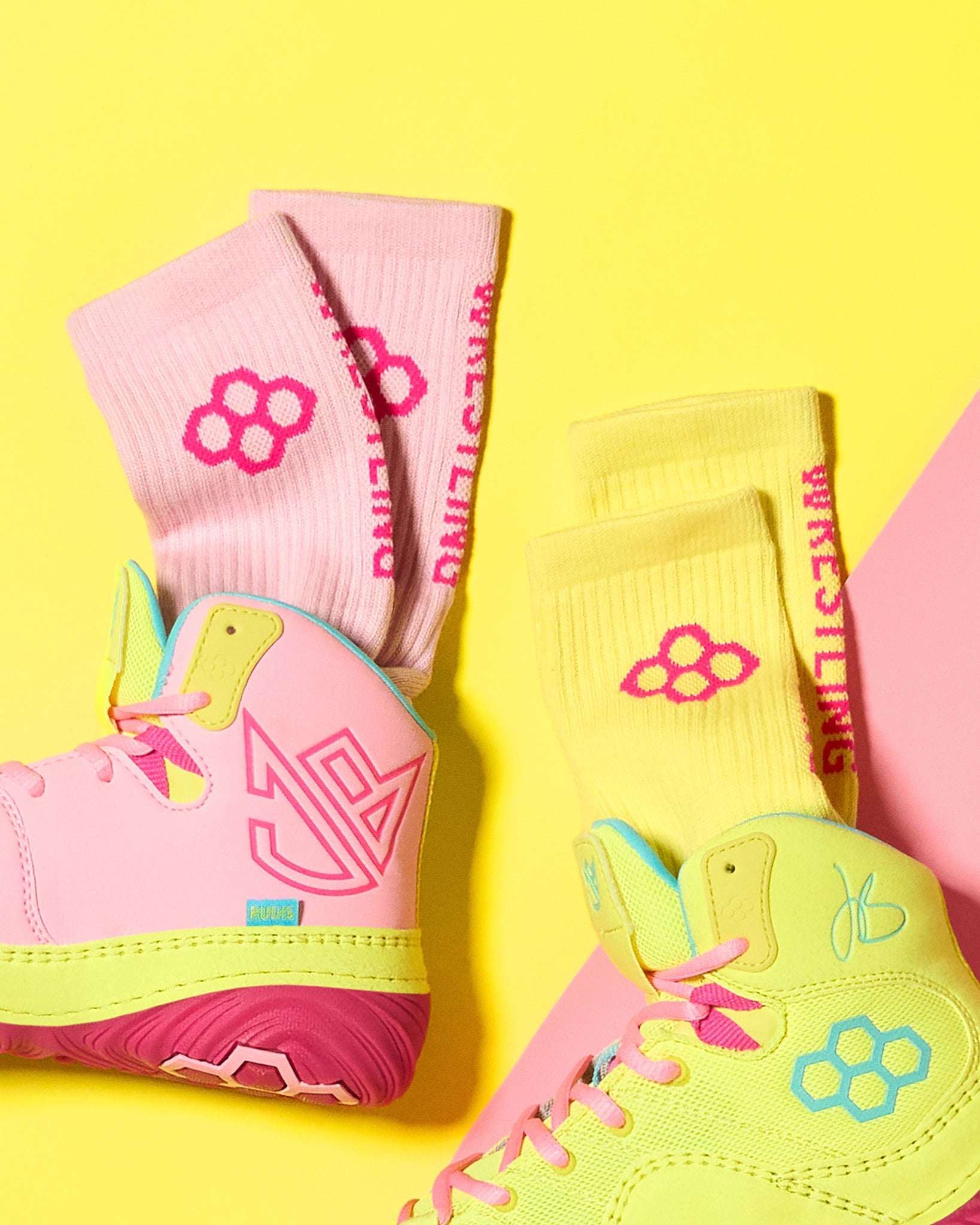 Pink and yellow wrestling shoes with matching socks on a yellow background