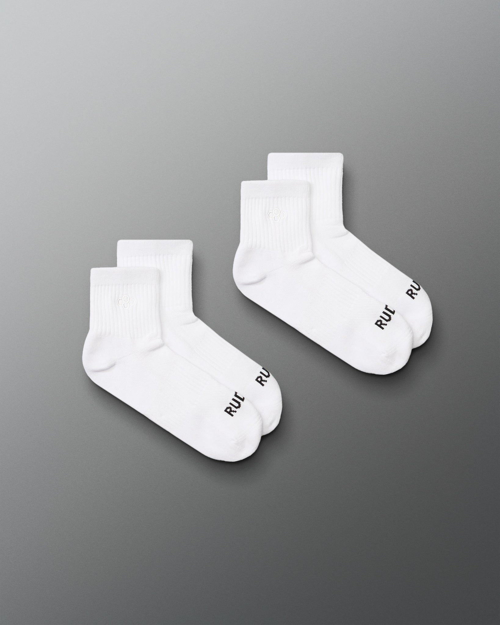 Two pairs of white socks with a brand logo on a gray background