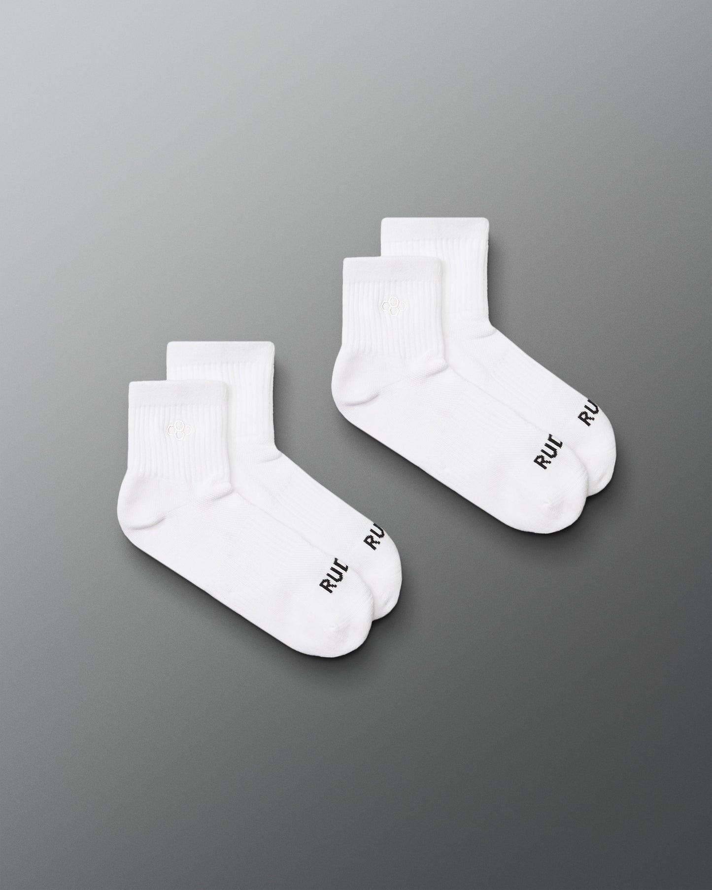 Two pairs of white socks with a brand logo on a gray background