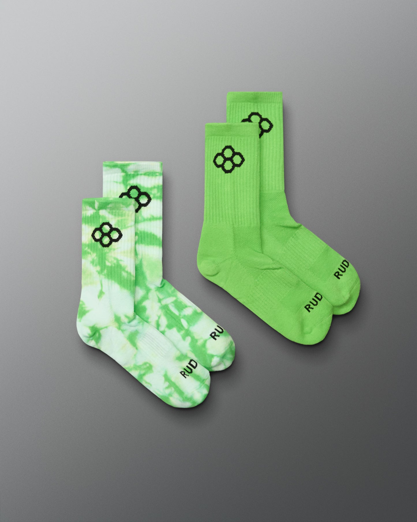 Two pairs of green socks with black patterns on a gray background
