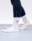 White socks with pink cross design worn with black leggings and colorful wrestling shoe on a neutral background