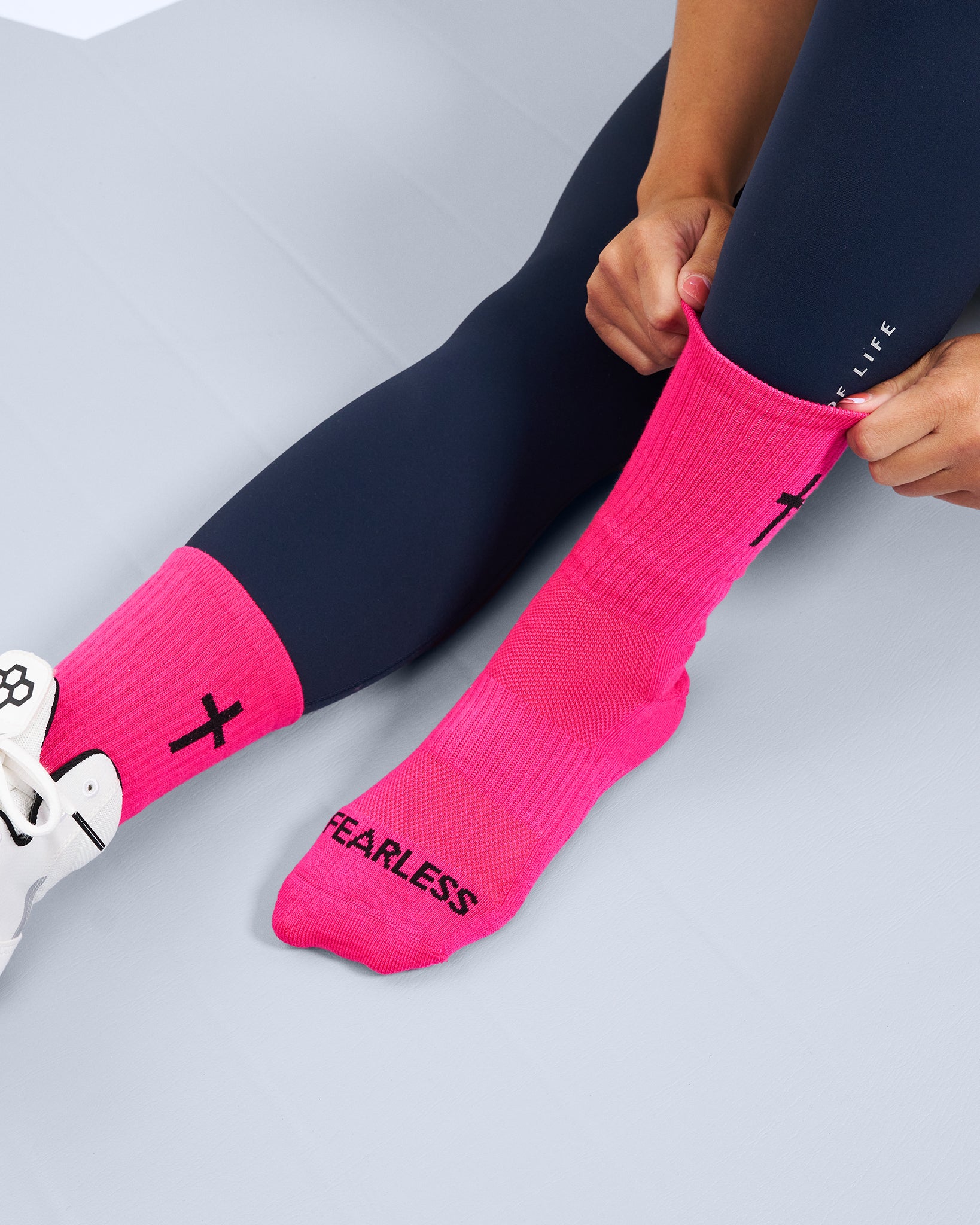 Person wearing pink socks with 'FEARLESS' text on a light gray background