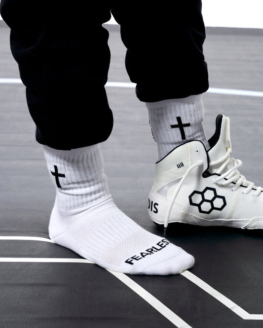 White wrestling shoes and socks with black symbols on a gray surface