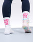 White socks with pink text worn by a person, standing on a light-colored floor.