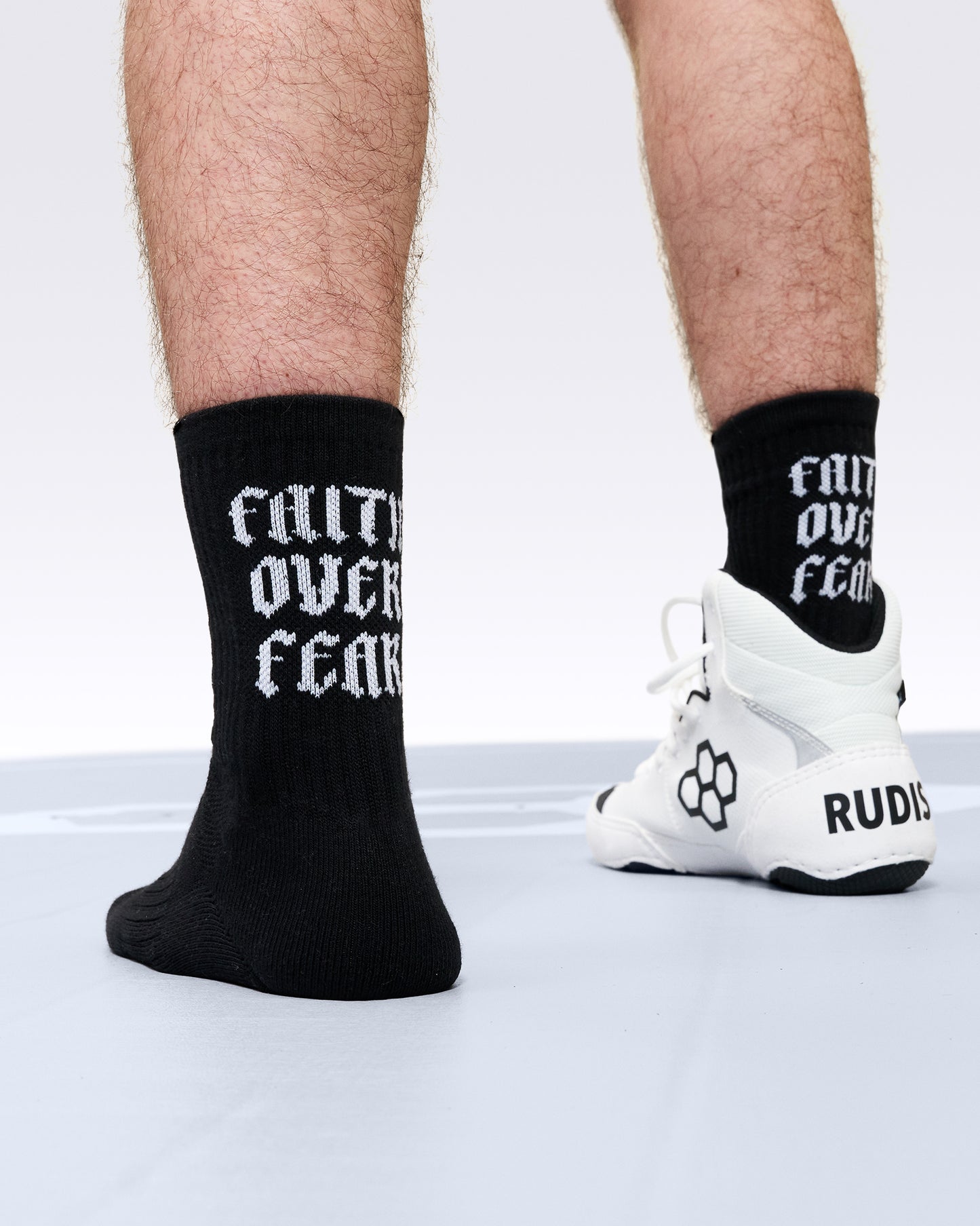 Black socks with white text worn by a person, paired with white sneakers on a light background