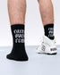 Black socks with white text worn by a person, paired with white sneakers on a light background