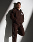 Person wearing a brown sweatsuit with visible branding against a white and gray background