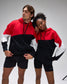 Two people wearing matching red, black, and white hoodies and shorts on a gray background